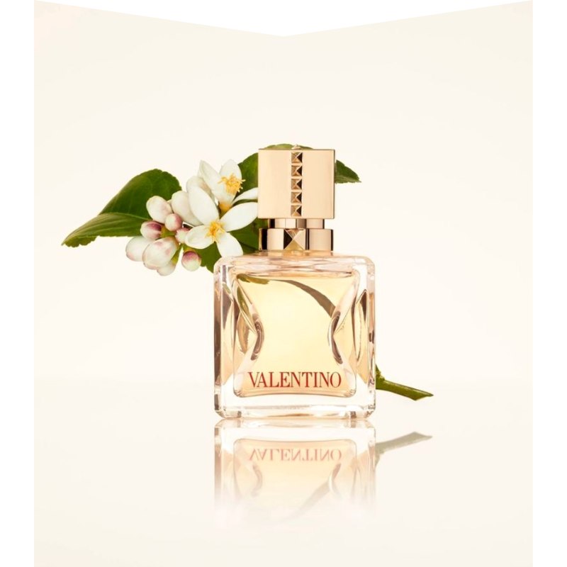 Perfume bottle with flowers behind.