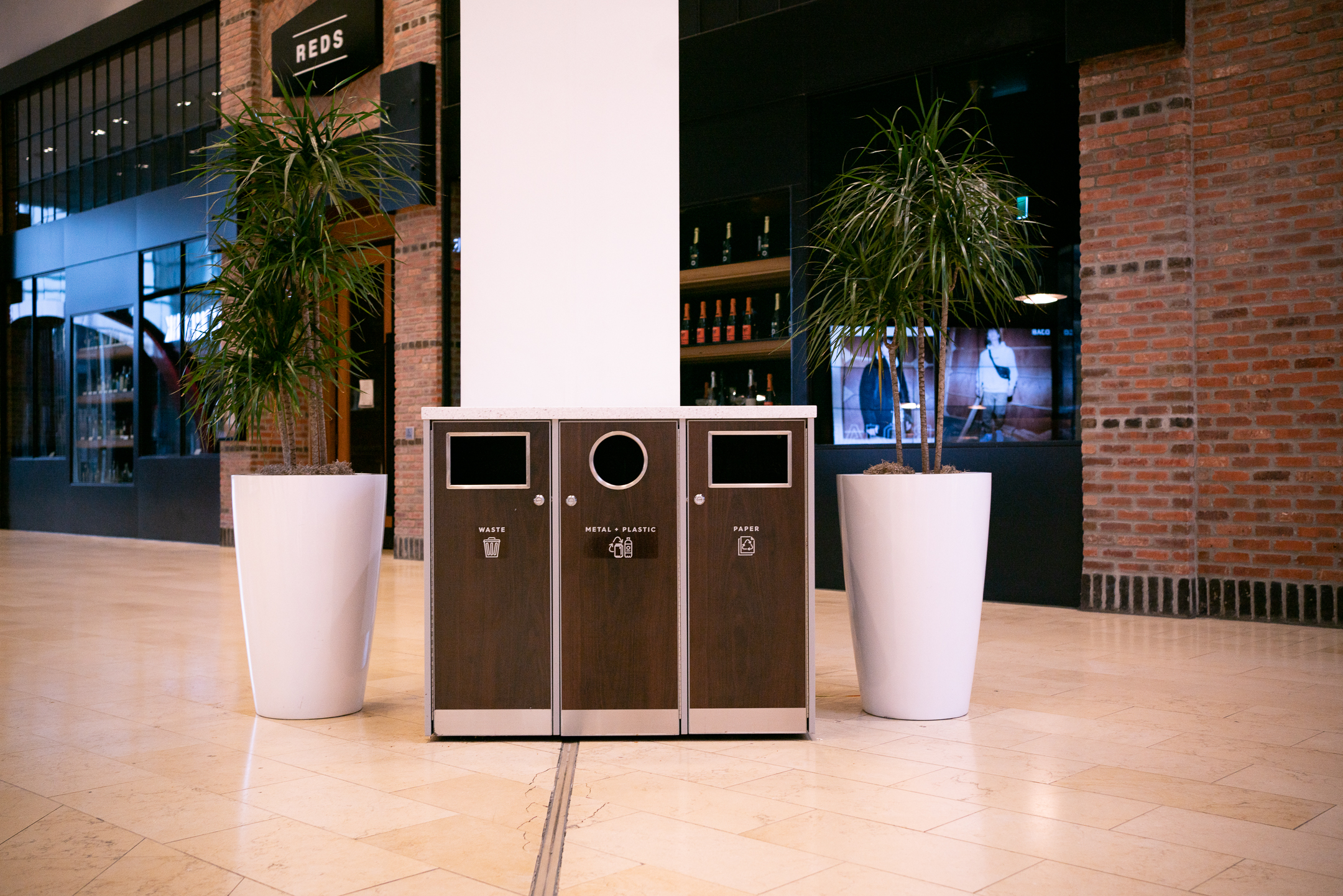 Three garbage bins beside one another for recycling, garbage, and plastic.