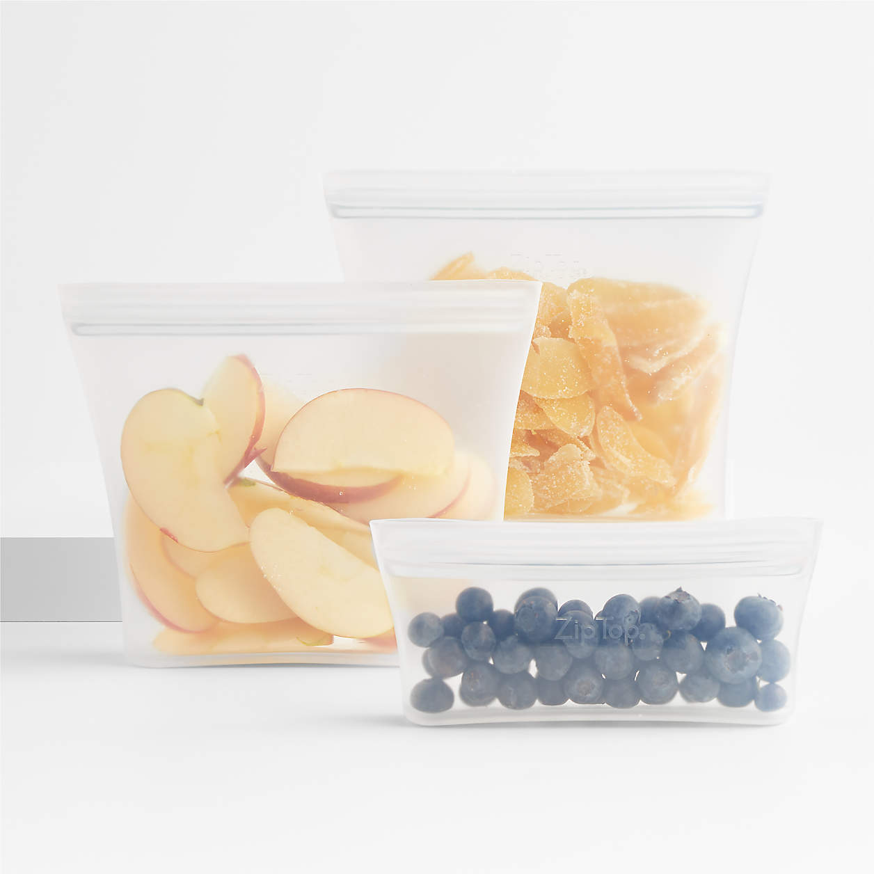 three reusable containers holding various foods
