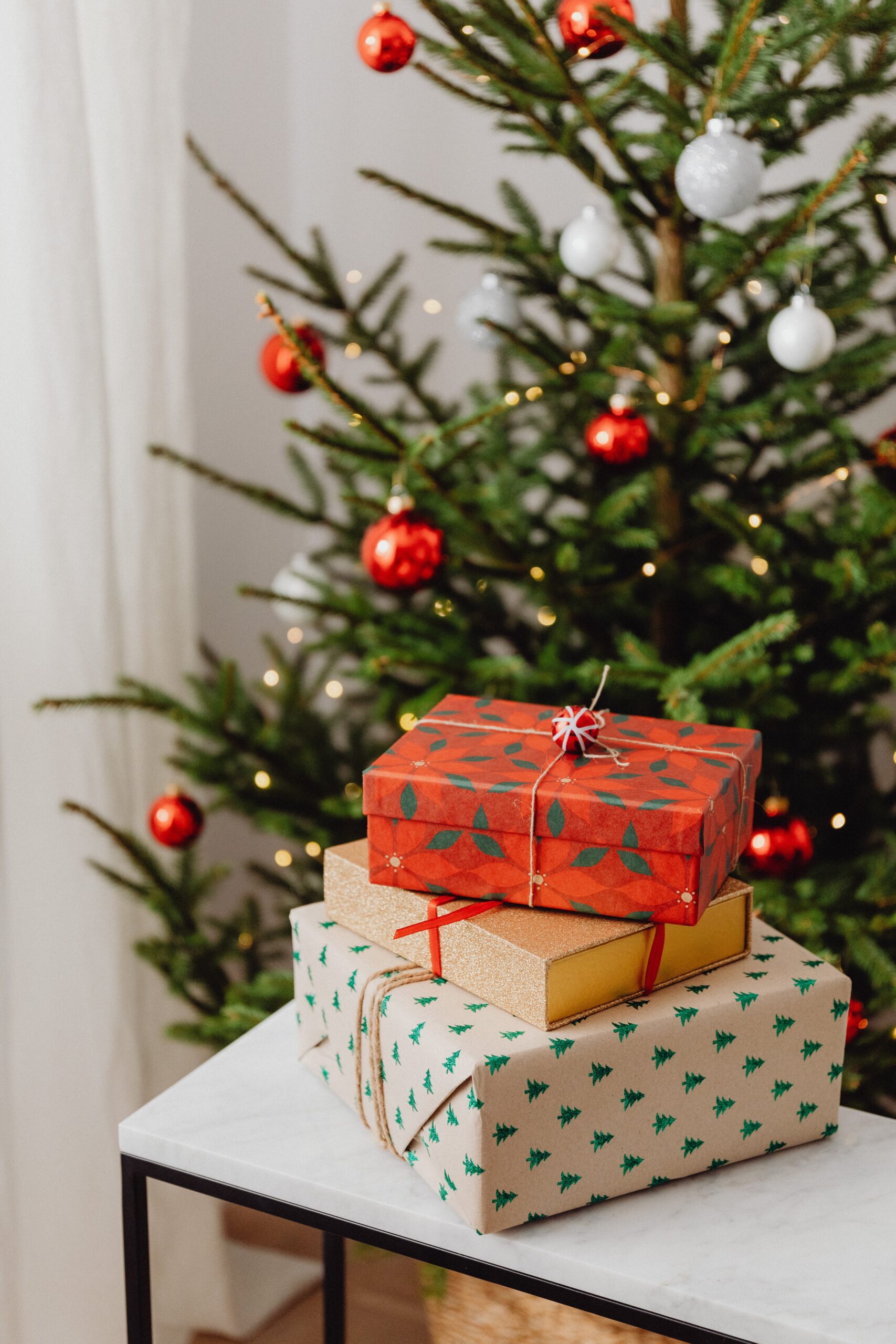 A stack of presents in front of a Christmas tree