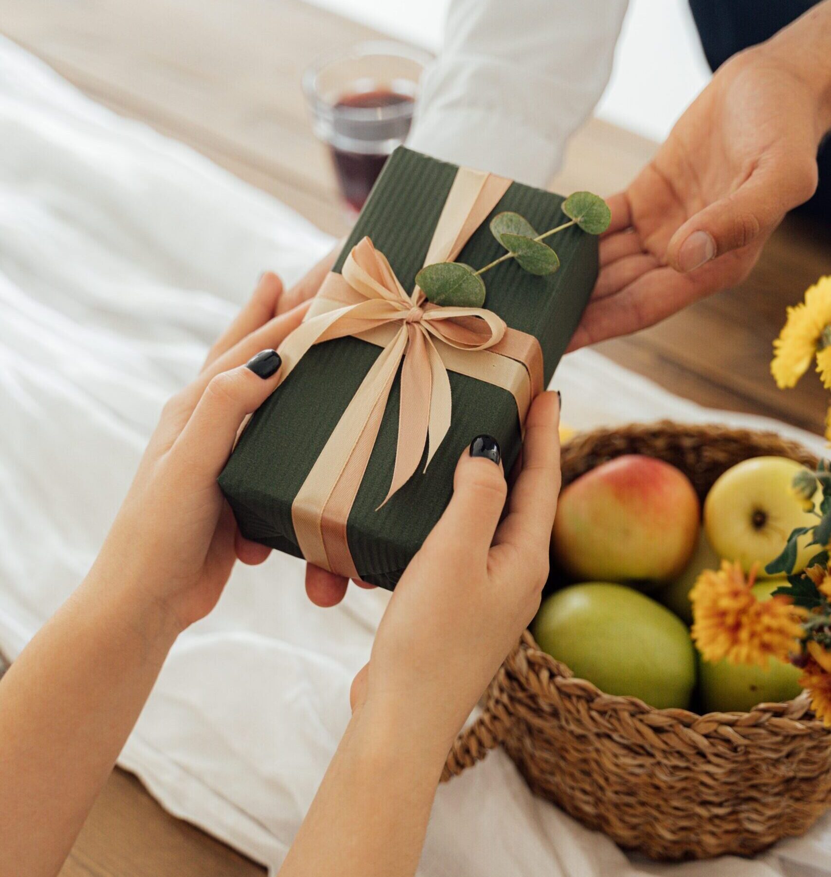 someone handing over a green gift box with pink ribbon to someone else