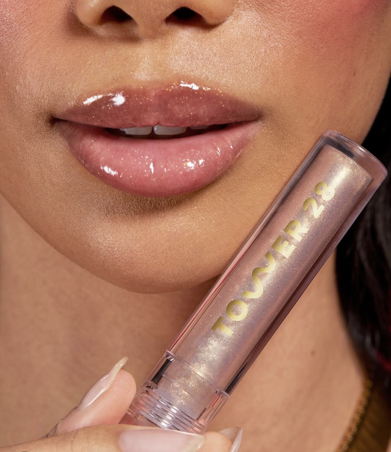 A close up shot of a woman's lips and a tube of lipstick