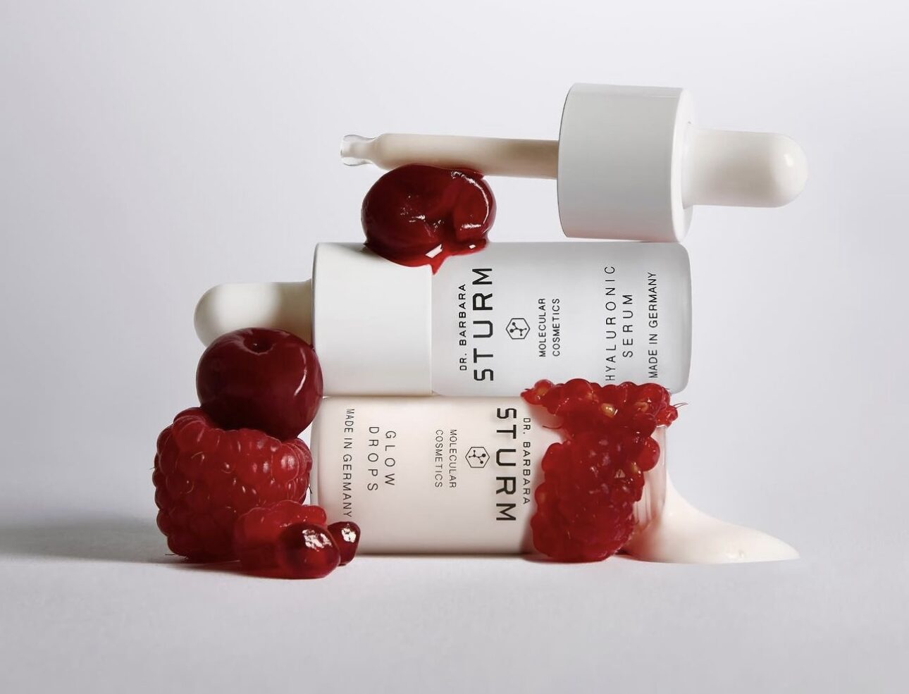 Two white bottles and some red fruit