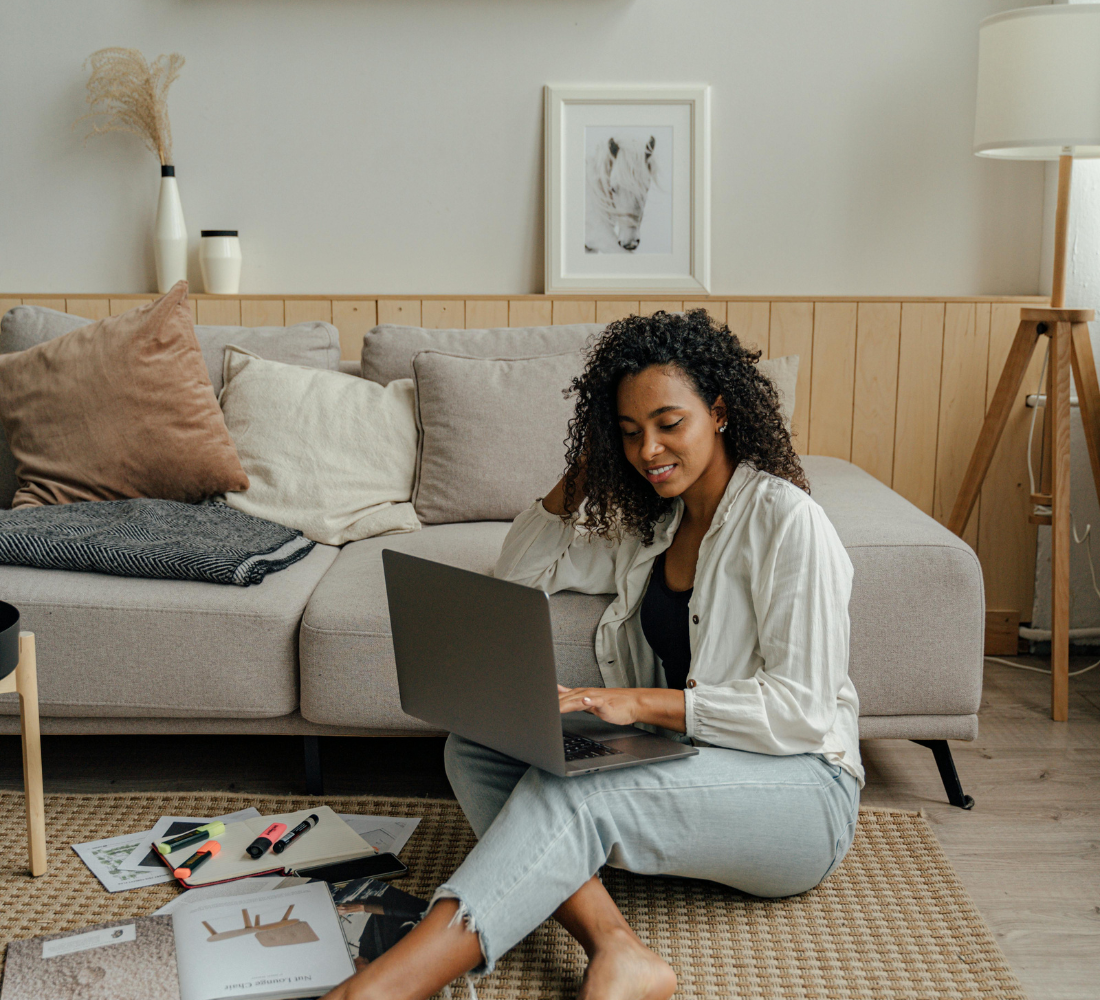 A woman sitting on the floor and using a laptop