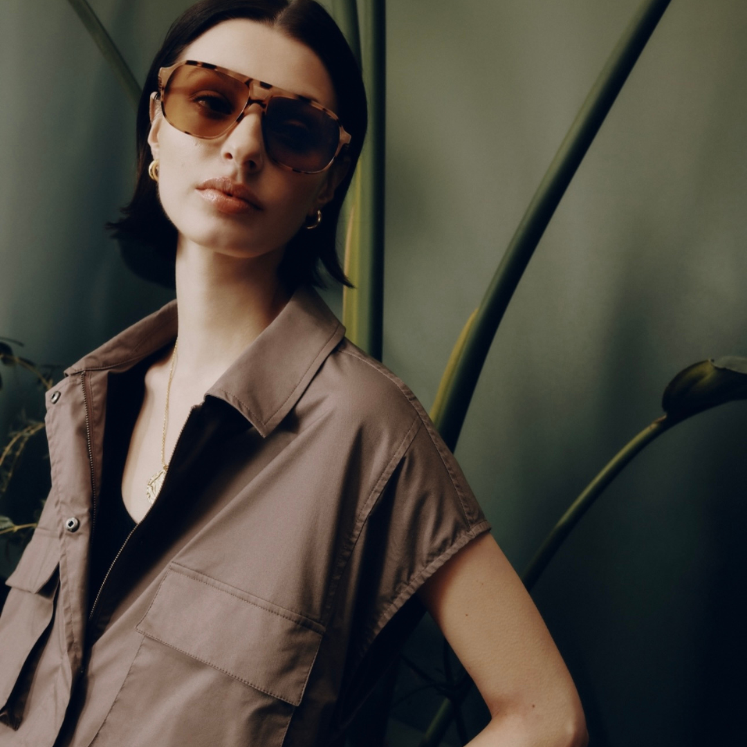 A woman wearing sunglasses and a short sleeve brown shirt