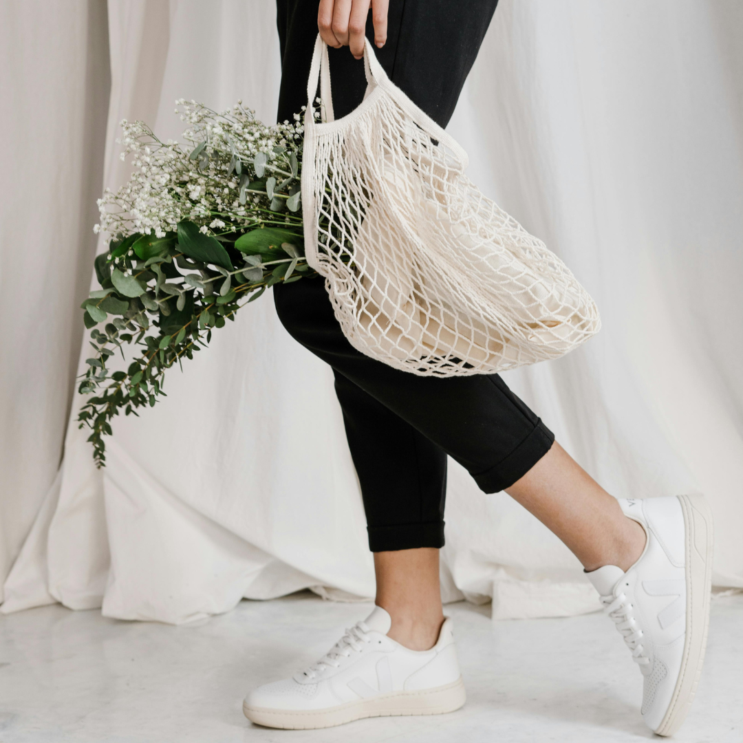 A person holding a mesh bag with a bouquet of flowers
